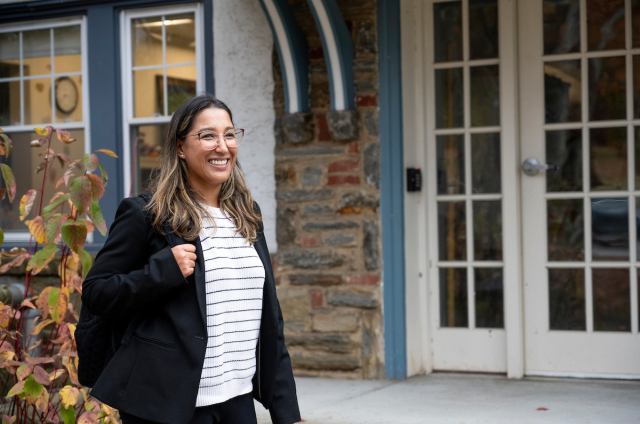 woman with a backpack walking in front of a house