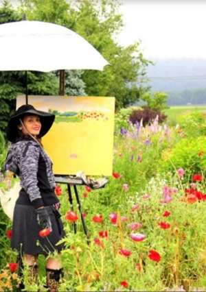 Monique Sarkessian standing in a field painting a picture