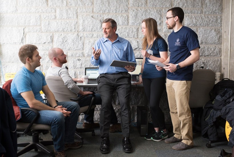 RISE Forum RISE Forum Director Karl Schmidt stands and talks with students in a classroom.