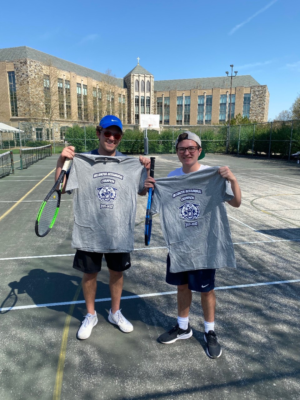 Two male students posing for doubles tennis champion photo
