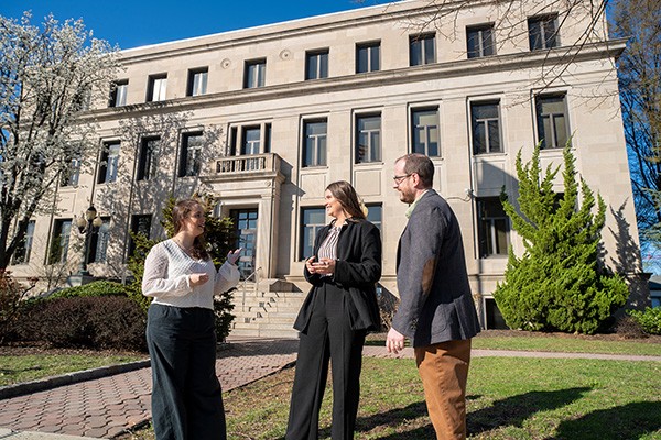 Two students and an alum from the Master in Public Administration program stand outside a township building. Two students and an alum from the Master in Public Administration program stand outside a township building.