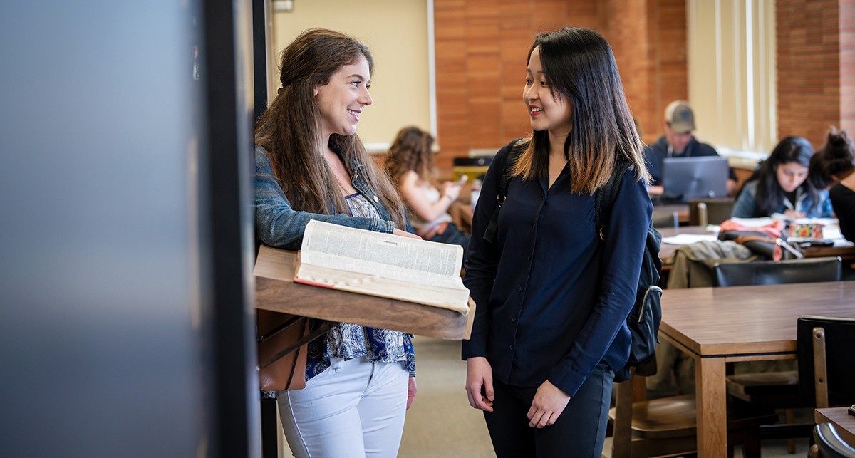 Graduate students standing and talking in the library