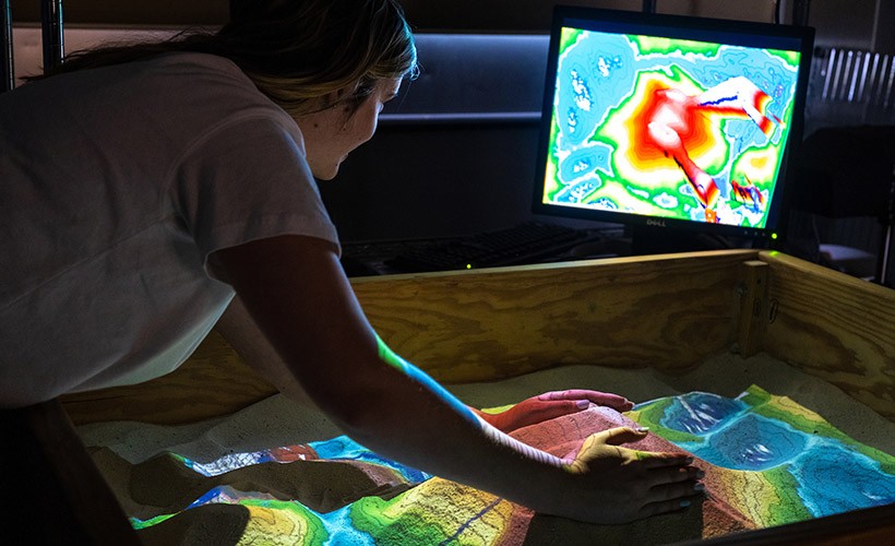 A student works in the augmented reality sandbox. image of student working at computer screen