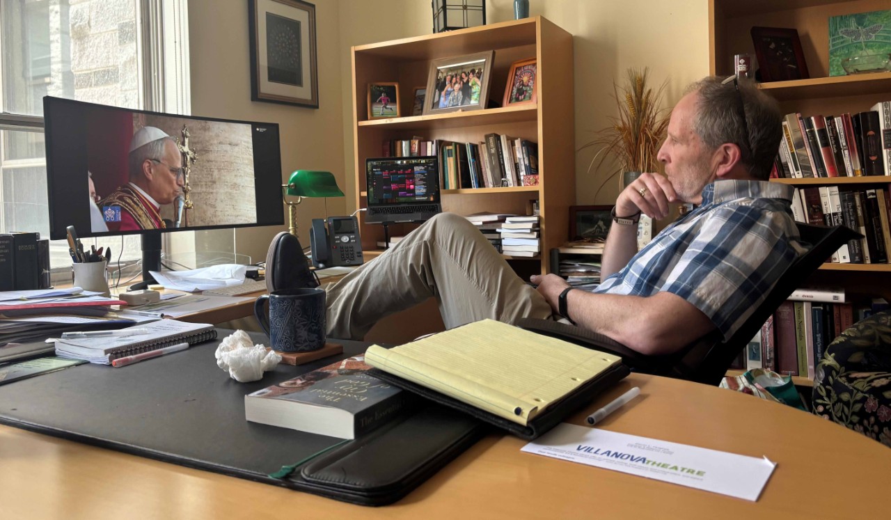 Kevin Hughes, chair of Theology and Religious Studies, takes a moment to himself to watch Pope Leo XIV 's introduction after celebrating the surprising announcement with colleagues.