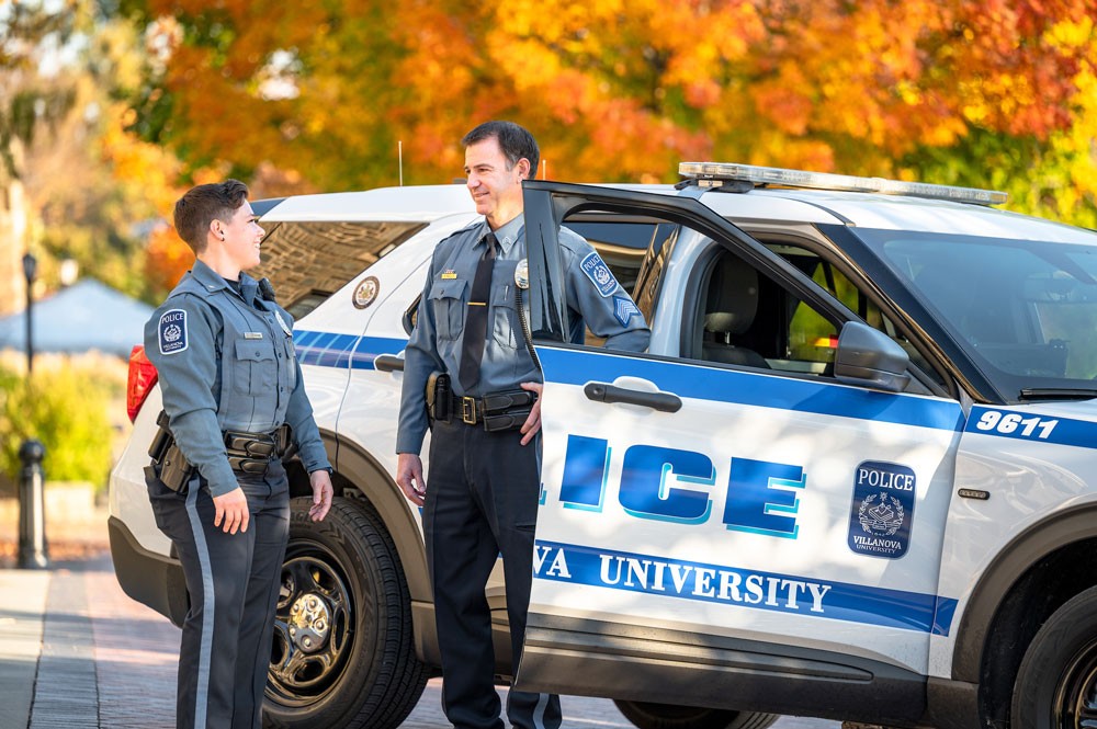 Villanova Public Safety Officer A male and a female public safety officer talk outside a patrol car.
