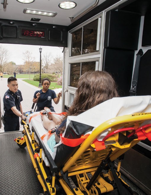Public safety on campus Two emergency response workers help someone in an ambulance