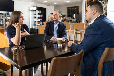 three people conversing in a coffee shop