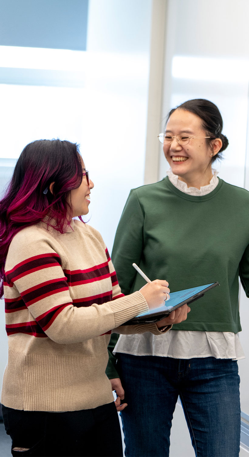 Female professor and student standing and smiling