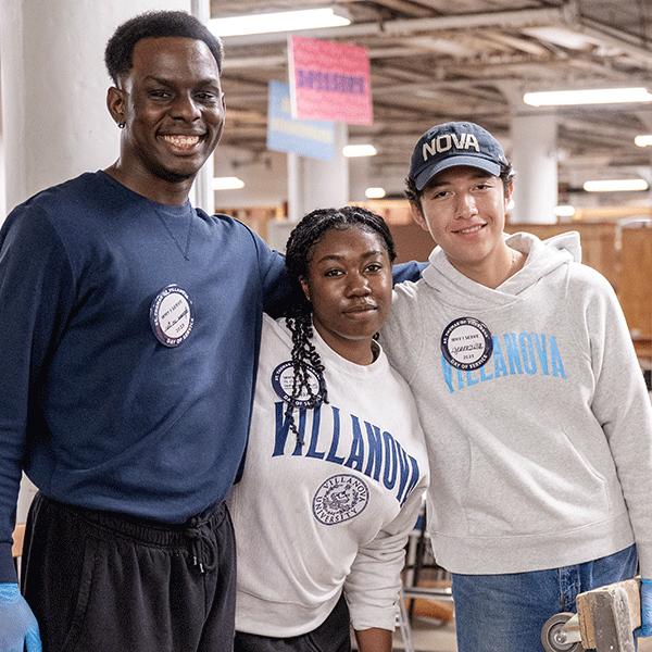 Three Villanova volunteers in a warehouse pose for a picture during Day of Service